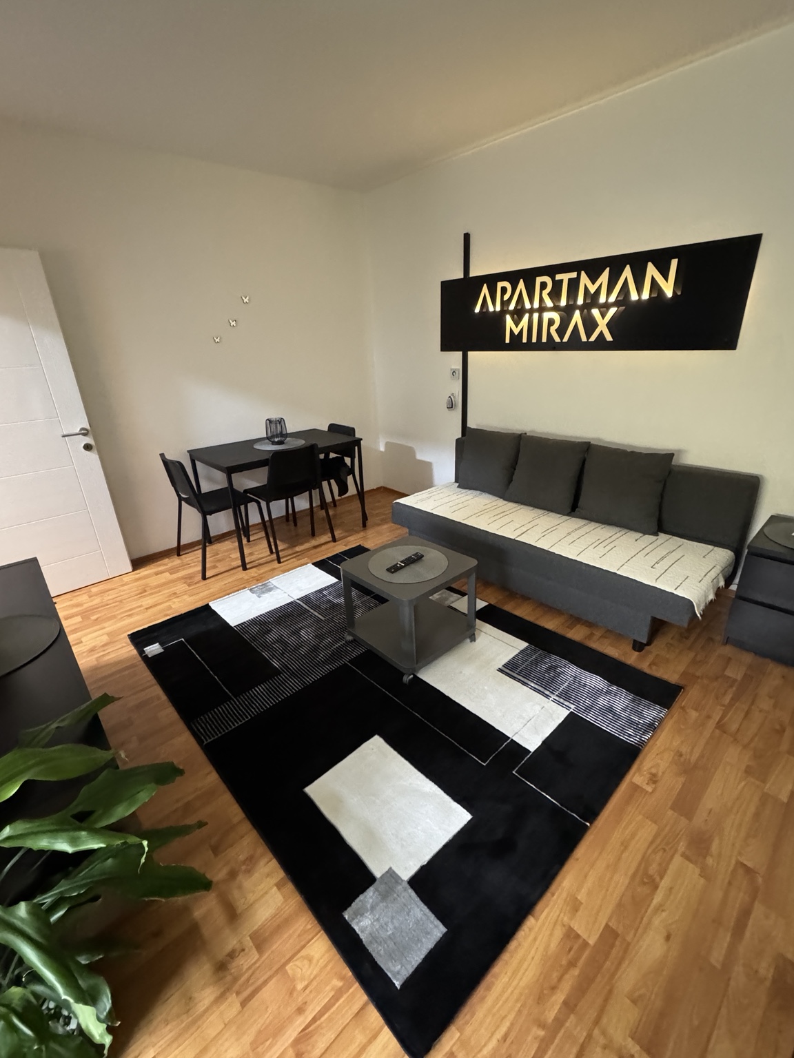 Dnevni boravak apartmana MIRAX sa sofom, stolom, tepihom i osvetljenim natpisom