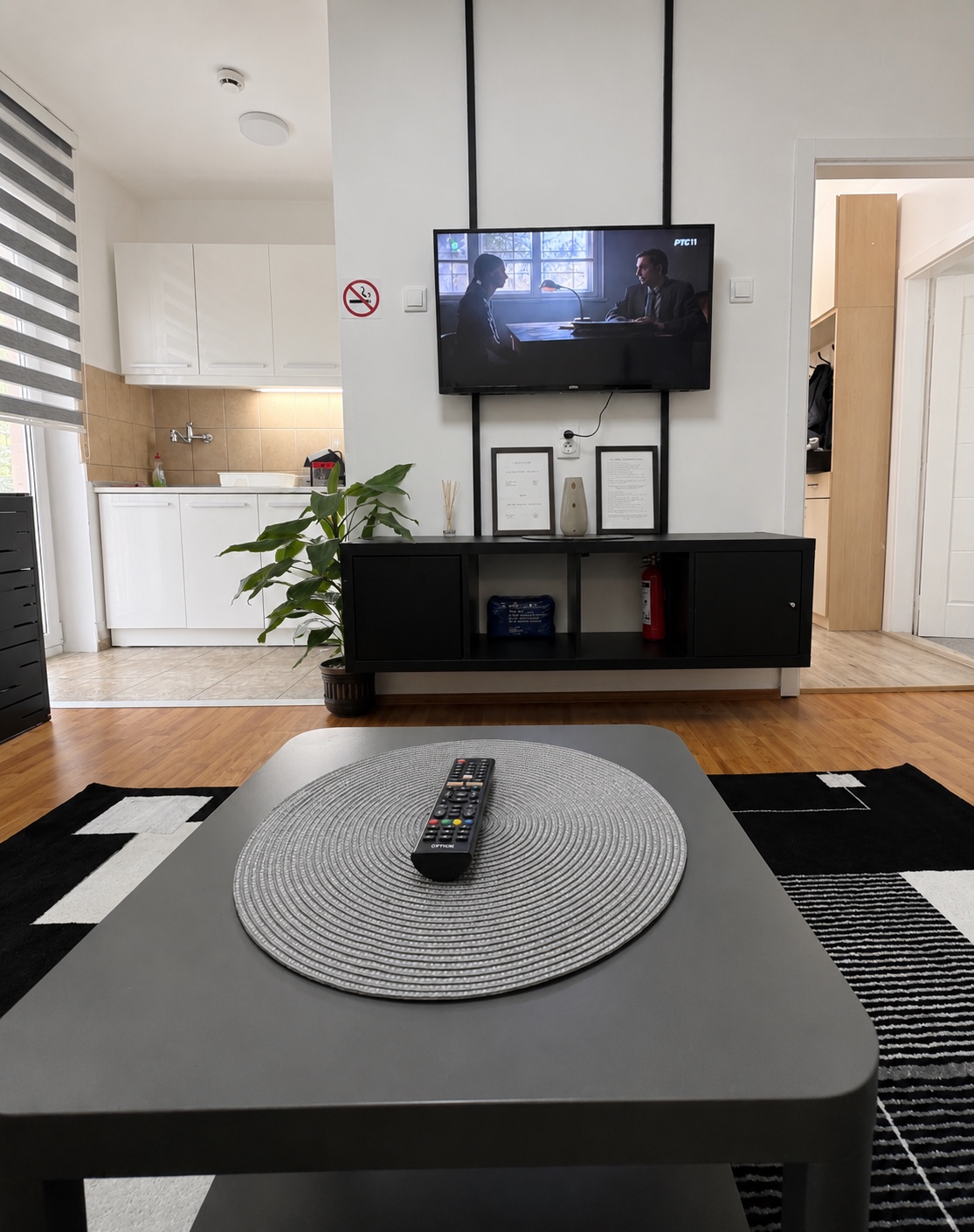 Televizor i komoda u dnevnom boravku apartmana MIRAX, sa kuhinjom u pozadini