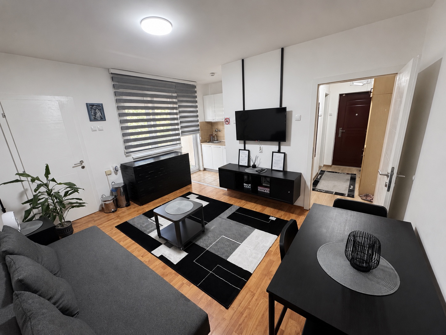 Dnevni boravak sa televizorom i trpezarijskim stolom, pogled ka ulazu u apartman MIRAX