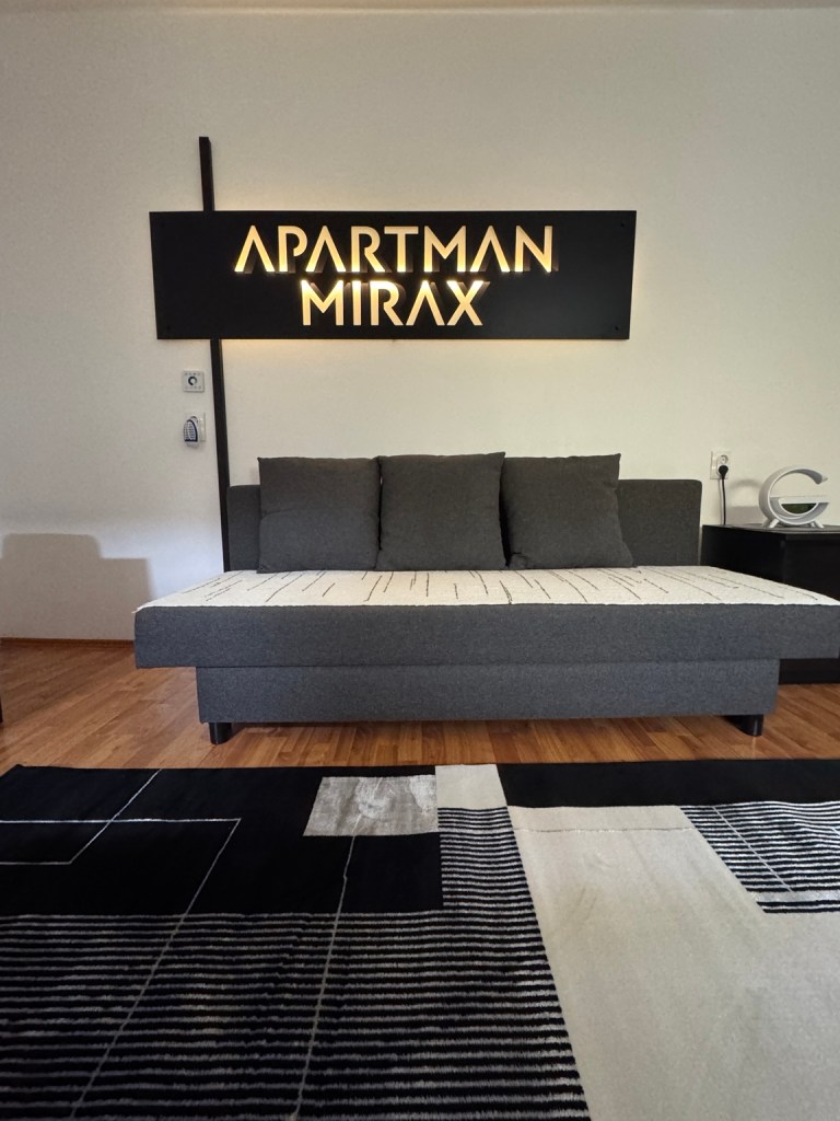 Sofa with cushions beneath the illuminated MIRAX Apartment sign