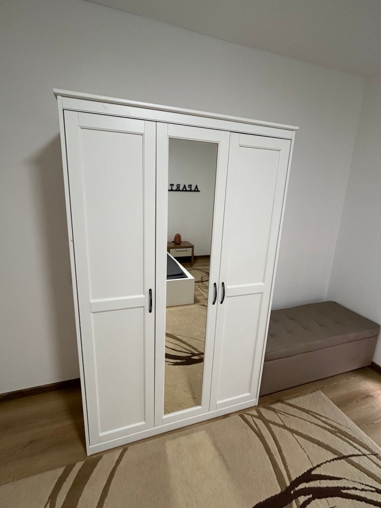 White wardrobe with a mirror and upholstered bench in the MIRAX bedroom
