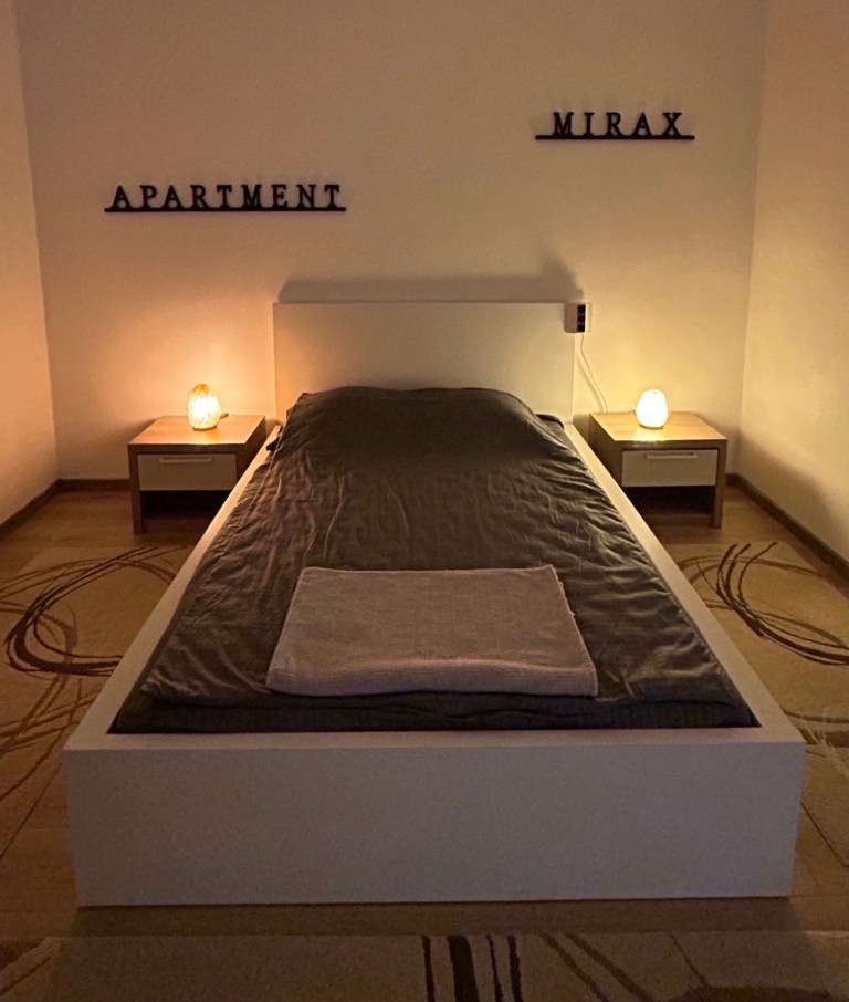 Freshly made double bed with towels and bedside lamps at MIRAX